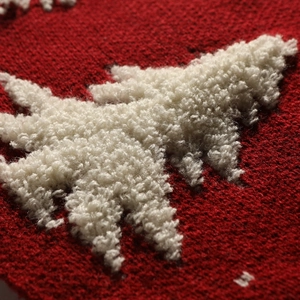 Red Christmas tree skirt with white plush reindeer embroidery in cozy knitted fabric