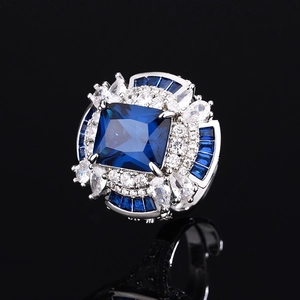 Exquisite silver ring with large square blue gemstone and white pear-cut accents on black background