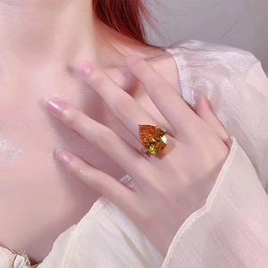 Detailed close-up of a pear-cut orange gemstone ring set in silver on a model's hand
