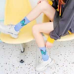 Detail of light blue combed cotton socks featuring butterfly patterns on a model