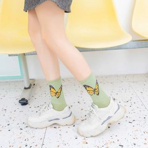 Detail of light green mid-calf cotton socks featuring large yellow butterfly patterns