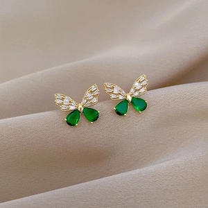 Detailed macro view of butterfly earrings with emerald stones and gold finish