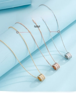 Detailed view of three cylindrical pendants in gold, rose gold and silver with zircon