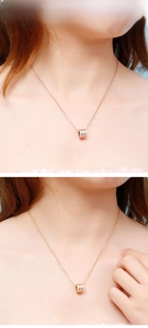 Detailed close-up of cylinder pendants with zircon settings in rose gold and gold finishes