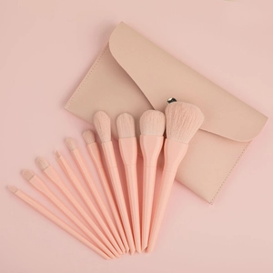 Flat lay of 10-piece coral pink makeup brush set with matching leather storage pouch