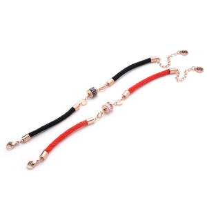 Close-up of woven couple bracelets with rose gold cylinder charms and lobster clasps