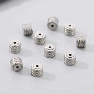 Macro detail of silver stainless steel cylinder beads with horizontal engraved textures