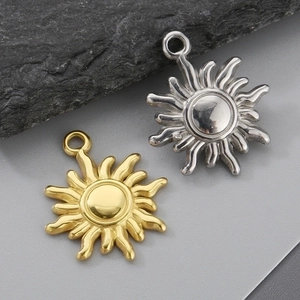 Macro shot of sun-shaped pendant charms in gold and silver finish on stone background
