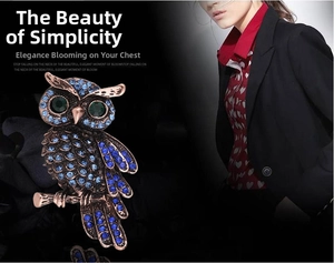 Macro shot of owl brooch featuring blue and green crystals on antique bronze base