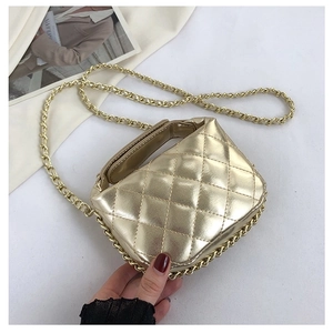 Detailed view of mini gold quilted handbag with woven chain strap on white background