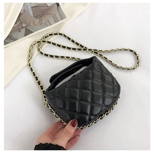 Detail of black quilted crossbody bag with gold chain strap and elegant rhombus pattern