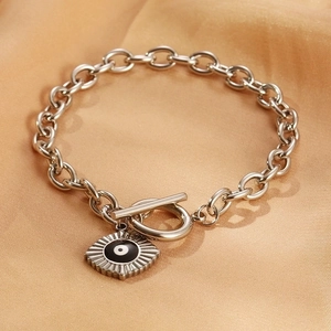 Macro shot of silver OT buckle chain bracelet with Evil Eye charm on orange satin