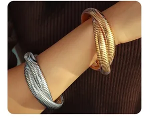Detail of gold and silver tubogas snake bone bracelets on a model with warm lighting