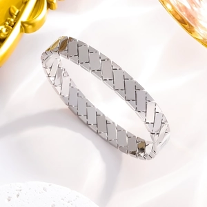 Silver geometric hollow woven titanium steel open bangle on white silk background
