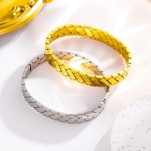 Detail showing gold and silver titanium steel bangles with woven cross patterns