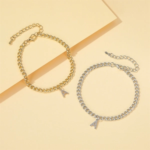 Bracelets de cheville dorés et argentés avec charms lettre A en strass sur fond beige