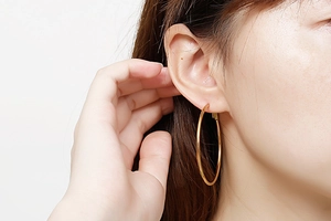 Vue latérale de grandes créoles dorées polies portées pour un style élégant