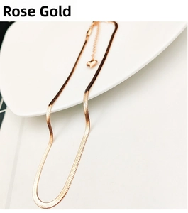 Detail of rose gold flat snake chain necklace with tiny heart pendant on white ceramic