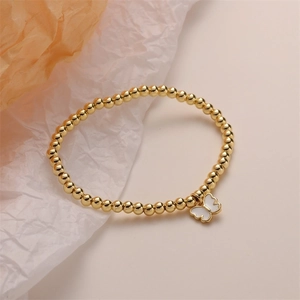 Close-up of golden beaded bracelet featuring an elegant white butterfly charm detail