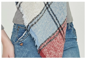 Close-up of thick blue plaid scarf with fringe details and warm boucle texture