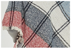 Detail of red and navy plaid scarf featuring woven texture and fringe trim accents