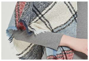 Close-up of red and blue plaid scarf with fringes on a grey knitted sweater