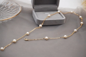 Detail of adjustable gold pearl necklace with stars-like freshwater pearls on grey tray
