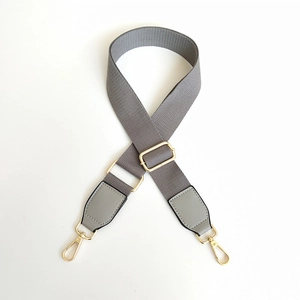 Detail of adjustable gray canvas strap with gold metal lobster clasps and leather ends