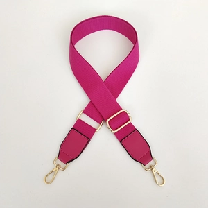 Detail of rose red canvas bag strap with gold metal buckle and leather ends