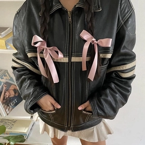 Close-up of a pink silk ribbon bow hair clip styled with a black faux leather jacket