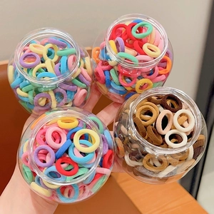 Close-up of four jars filled with colorful candy and earth tone nylon elastic hair ties