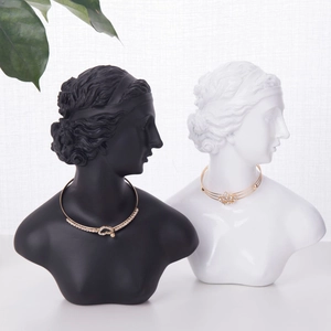 Set di collane dorate con strass esposto su un busto di scultura classica bianca