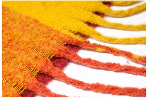 Macro shot of yellow and orange plaid knit fabric texture with thick fringe details
