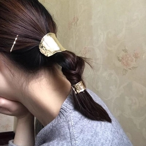 Detail of golden irregular hammered metal hair tie cuff on low ponytail