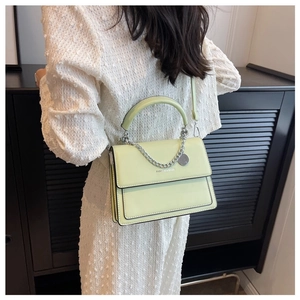 Model wearing a pale yellow crossbody bag with silver chain and Fashion & Bags text