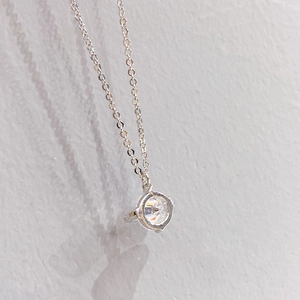 Detailed view of silver cable chain with a round cubic zirconia pendant in 4-prong setting