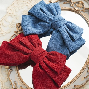 Detail of burgundy and denim blue oversized layered bow hair clips on a vintage mirror