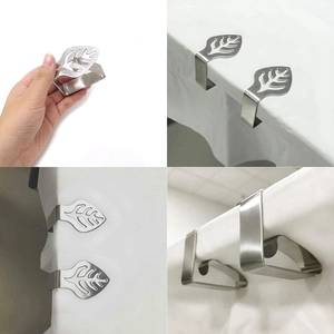 Detail of leaf shaped stainless steel tablecloth clips being applied to a table edge