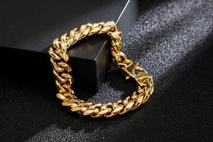 Close-up of polished gold Cuban link bracelet with box clasp on dark background