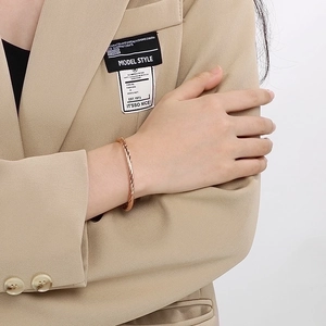 Close-up of twisted rose gold stainless steel bangle bracelet on woman wrist