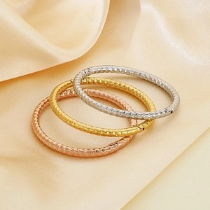 Macro shot of three-piece stackable textured bangles in gold, silver, and rose gold