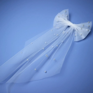 Elegant white bridal bow veil with pearl accents on a clean blue background