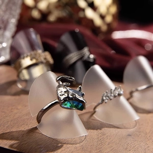 Antique silver ring with blue-green gradient gemstone on geometric jewelry display stand