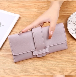 Detail of light purple wallet with pebbled leather texture and wide strap buckle closure