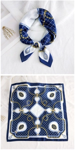 Detail of navy and white square silk scarf featuring golden chain and grid patterns