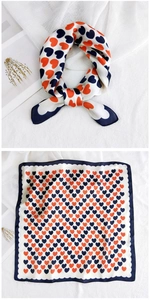 Detail of square silk scarf with orange and navy heart patterns and wavy edges