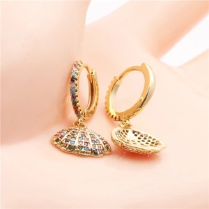 Golden shell earrings with colorful zircon stones held between fingers in a close-up view