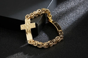 Macro shot of gold Byzantine chain bracelet with hammered cross pendant on black texture