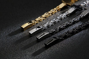 Macro shot of Byzantine stainless steel chains in gold, silver, dark gray, and black finishes