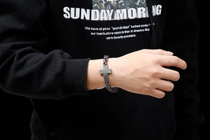 Close-up of black titanium steel cross bracelet with vintage cuban chain for men